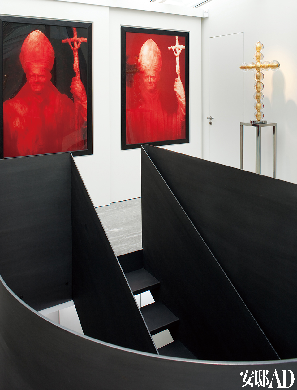 空间中的画廊部分。由Elliott亲手打造的黑钢打蜡楼梯无疑是其中的焦点。两块红色的画作是Andres Serrano的《红色的教皇》（Red Pope）。立在搁架上面的十字架来自Jean-Michel Othoniel。