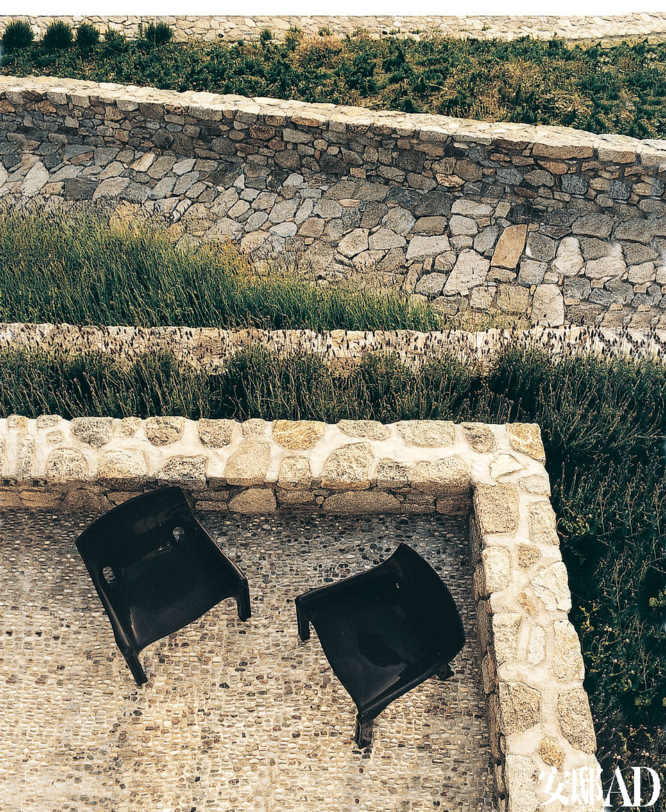 俯瞰粗砺石块夯筑成的露天平台，简洁的黑色座椅更添一份坚毅之美。
