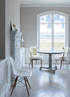 客厅一角用一张云纹色调的圆桌布置出简单的进餐角落。两把18世纪的瑞典古董椅既有时代的特征，又在色彩上有所跳脱。地板和木窗框都是Sylvie极力要求保存下来的这套公寓的初始面貌。