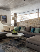 地面层的客厅里，舒适的沙发角落温馨宜人，墙面是由天然石材料制成的。