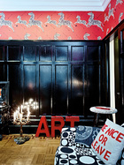 红色的ART字母组合与Piero Fornasetti的凳子都来自eBay，原来的木地板得到了保留。古典蜡烛形台灯是在路易斯安那一座伏都教建筑中发现的陈年旧物，也是从Etsy网上低价淘来的。斑马图案的红色墙纸源 自于主人最爱的电影场景，完全打破了原本黑色护墙板的沉闷。
