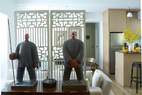 这个家门口站岗的两尊玻璃纤维的雕塑“农民”像出自艺术家刘若望之手，购自香港的WellingtonGallery。雕塑后面是两扇经过刷白的古董中式门，为后方的起居室提供了私密感。