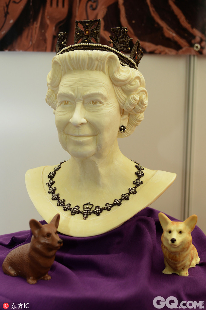 当地时间2016年10月14日，英国伦敦，作为英国巧克力周的一部分，一场巧克力的盛宴在奥林匹亚展览中心上演，其中伊丽莎白二世女王的雕塑旁，贴心的带上了女王心爱的两只宠物。