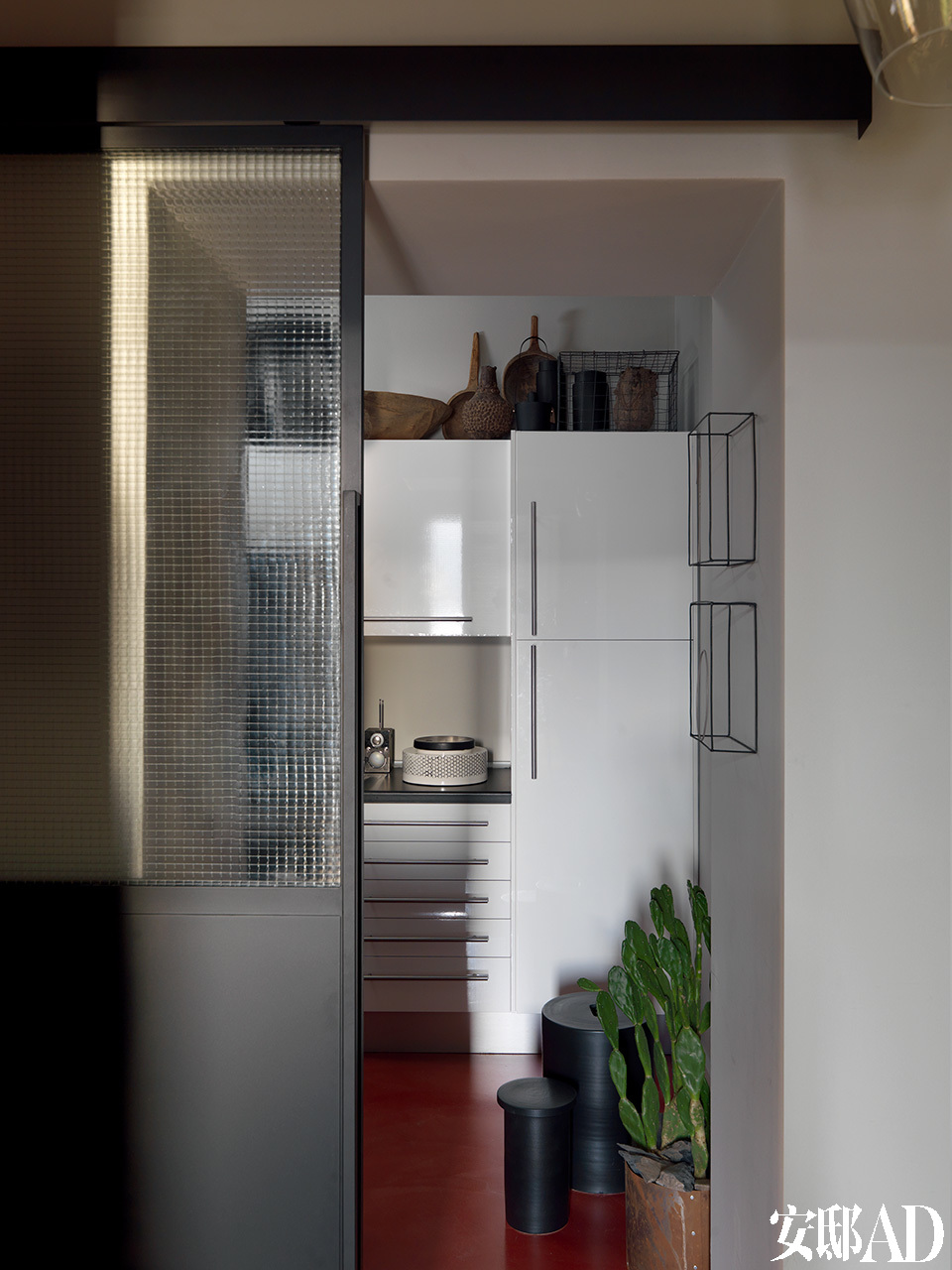 工业风格的滑动门可以通往家中的厨房，厨房的架子上陈列着一系列民族和现代风格的物件，为原本稍显平淡的厨房增添了质感和氛围。厨房墙壁上的金属丝雕塑是由Antonino Sciortino创作的。