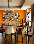 这个圆形的中式餐桌是这个家的“核心”，主人补起餐桌对面原本为落地玻璃的这面墙，刷成具有西班牙风情的橘色，再挂上朱铭代表作品《人间系列》，都是为了一个“暖”字。