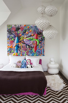 充满艺术气息的儿童房，即便难逃粉红也还是与众不同。主人女儿的卧室，墙上挂着Kenny Scharf的代表性画作《Junglicious》，白色吊灯是20世纪60年代由Vest出品的。条纹图案地毯来自Doris Leslie Blau，床头柜是Robert Kuo的设计。