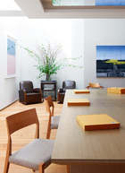 位于负一层的餐厅中，左侧墙上的淡粉、淡蓝色画作是艺术家谭平的版画作品，沙发和佐餐车是20世纪30年代上海AreDeco风格的古董家具，购自上海。正面墙上的油画来自艺术家张晓刚，主餐桌为定制品，餐椅是日本设计师的作品。
